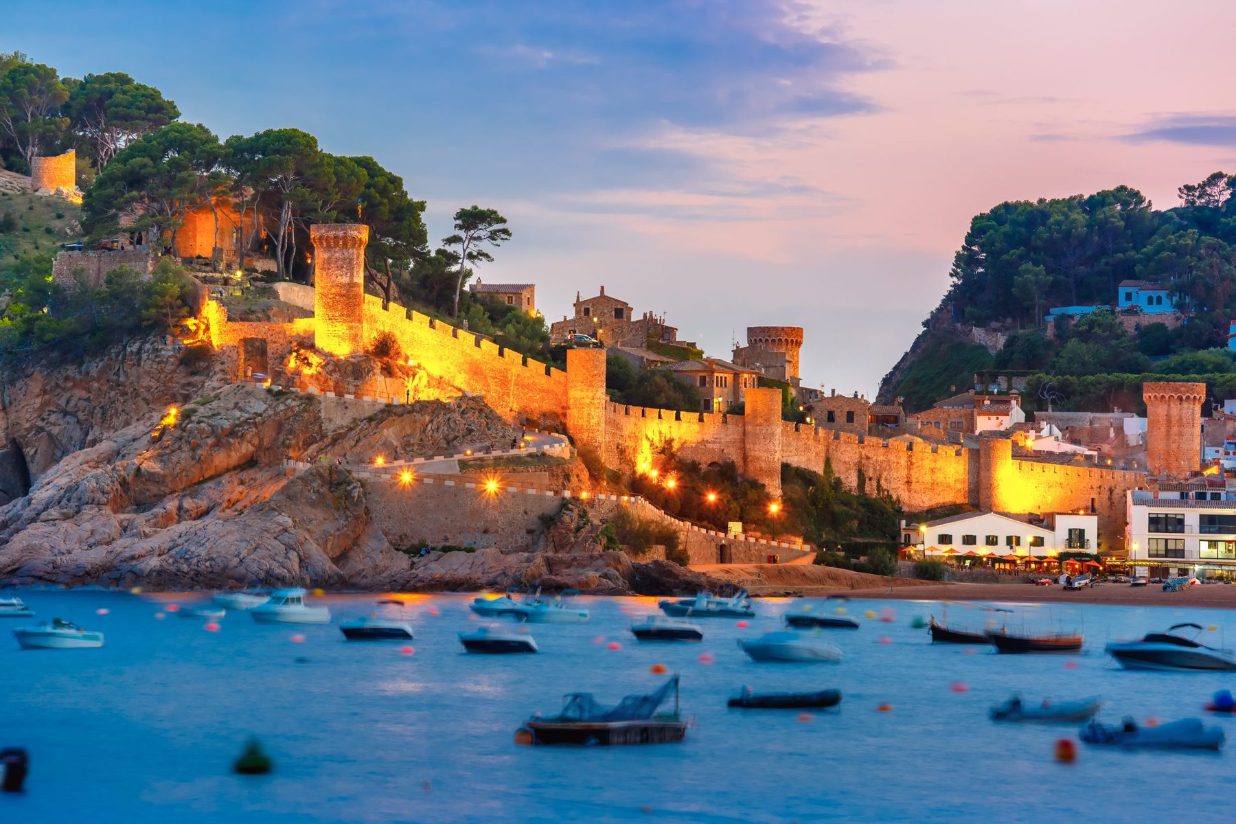 The lit medieval walls of Vila Vella above the bay of Tossa de Mar at dusk